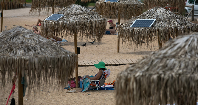 Atina plajlarında güneş enerjili telefon sarj şemsiyeleri